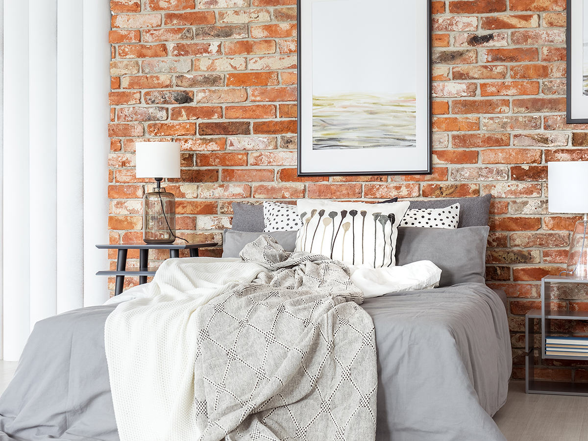  photograph of bedroom with exposed brick wall